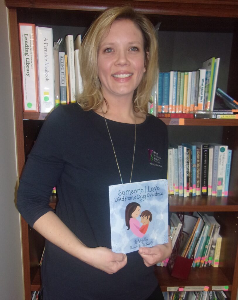 Melody Ray, Volunteer Coordinator/Grief Specialist, posing with her book
