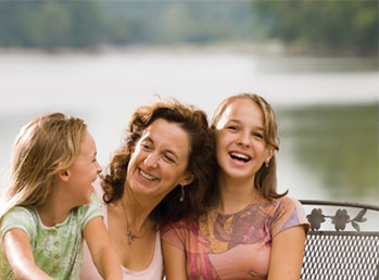 a mother smiling with two children on a bench