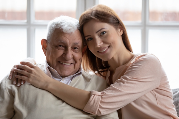a woman embracing an older man as they both smile at the camera